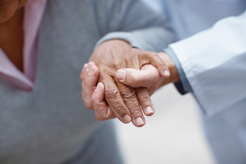 Closeup of an old woman's hand being held by a doctor