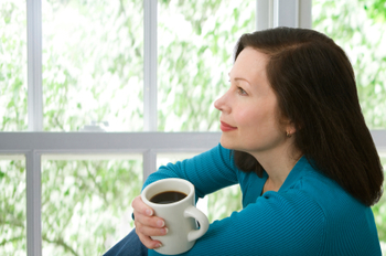 woman sitting by a window with coffee