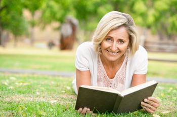 Senior Woman Reading In The Grass